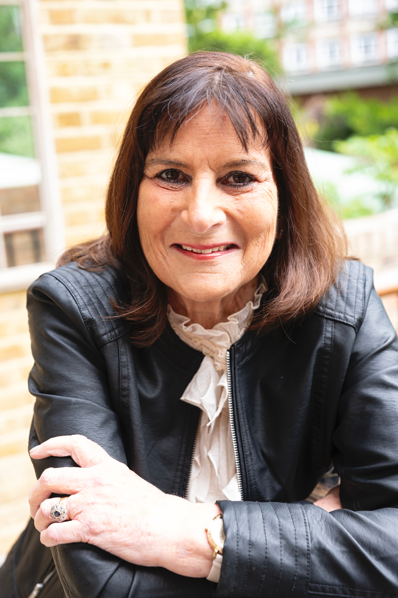 Portrait of Victoria Tomlinson in a black leather jacket seated outdoors
