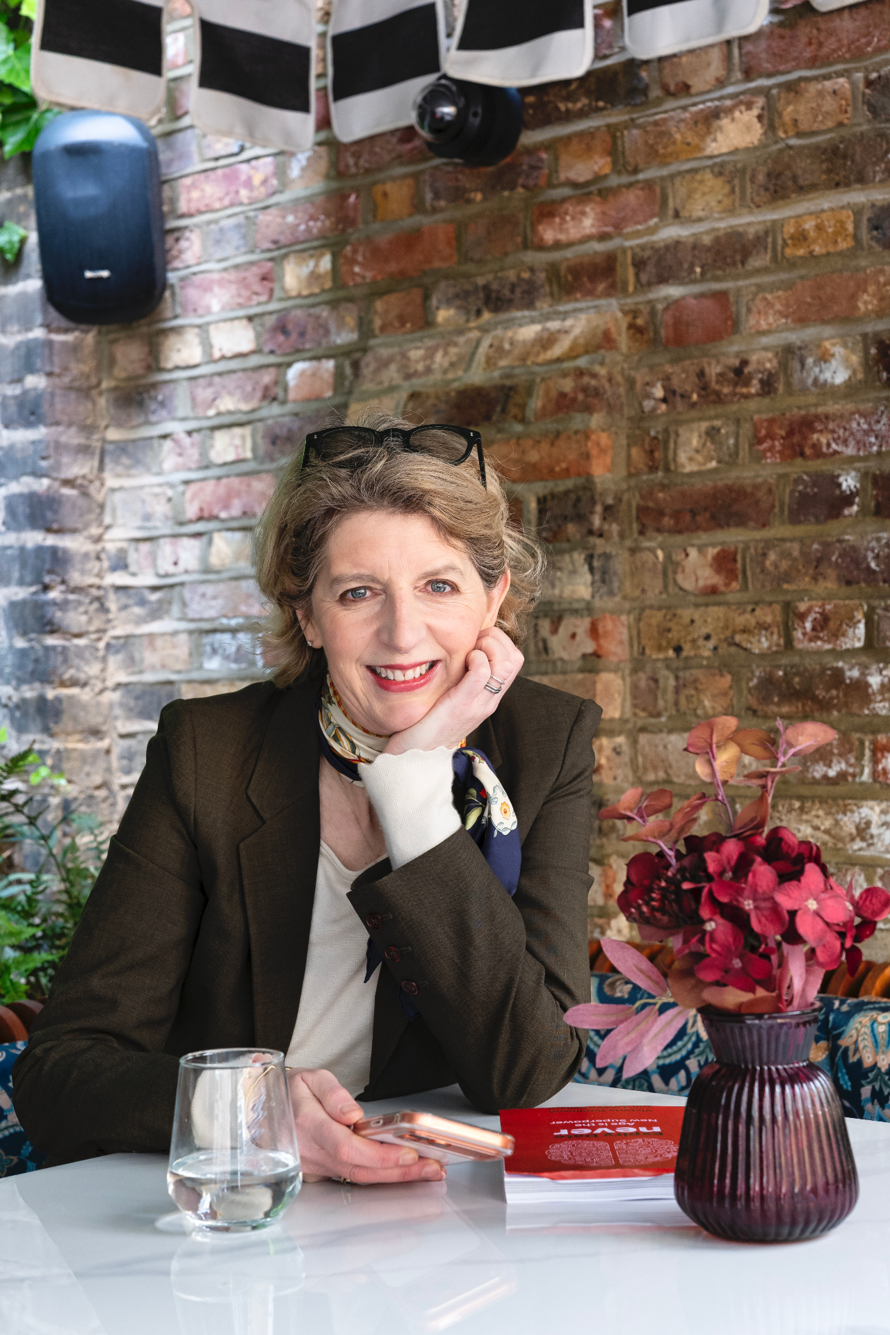 Portrait of Louise Ballard seated at a table with flowers and a book